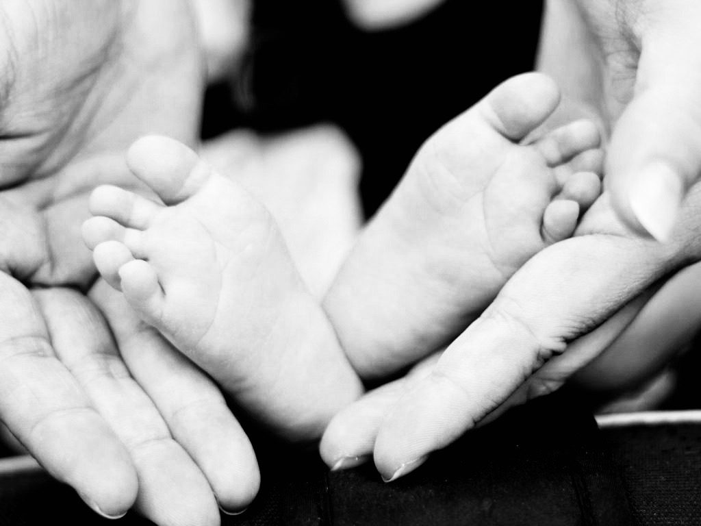 Pieds de bébés dans les mains d'un parent dans un contexte de médiation familiale ou de droit de la famille.